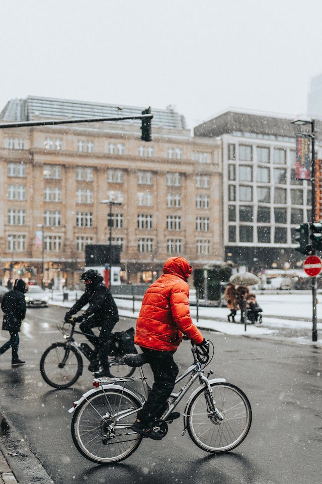 Gens faisant du vélo dans la rue en ville en hiver